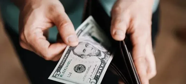 Hands taking five-dollar bill from leather wallet