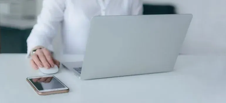 Woman at white desk with laptop and smartphone
