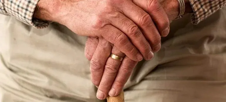 Elderly man's hands resting on walking cane