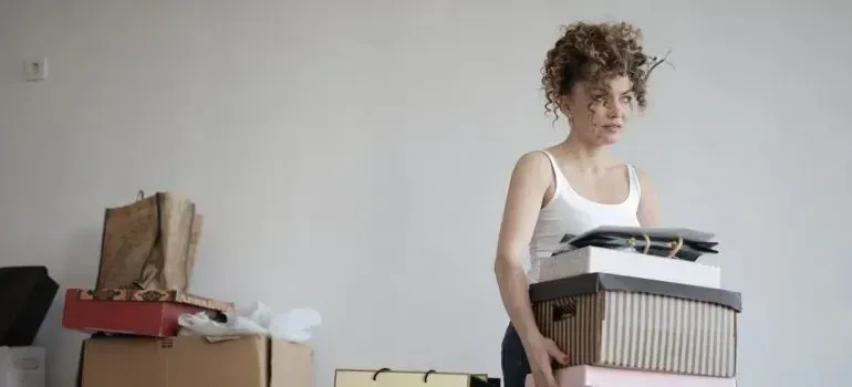 Woman carrying stack of storage boxes while packing