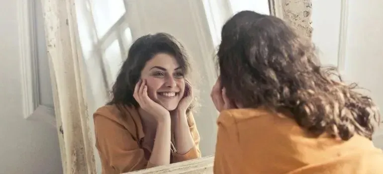 Smiling woman looking at herself in vintage mirror