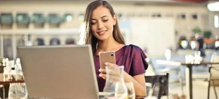 Woman with phone and laptop at outdoor cafe