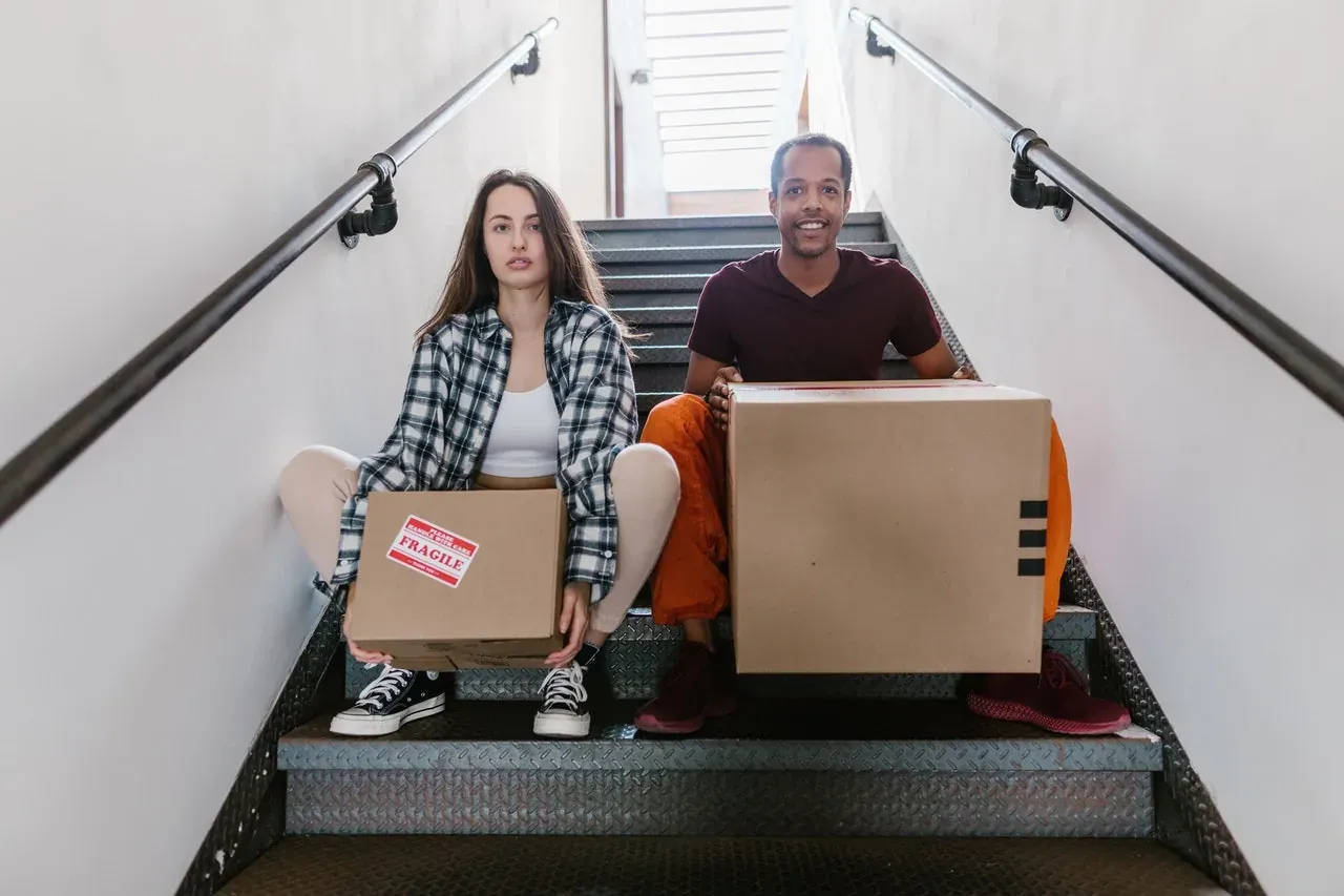 Couple with boxes on staircase