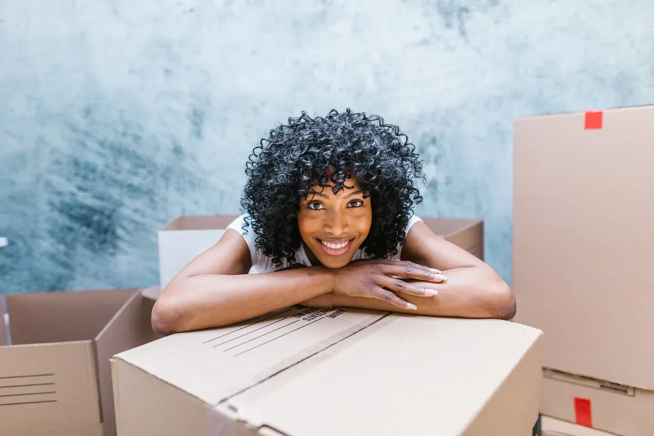 Smiling woman resting on cardboard box