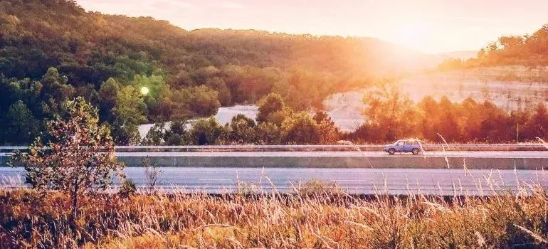 SUV driving on rural highway at golden sunset