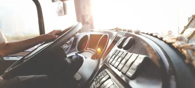 Driver's hands on truck steering wheel, sunlit cab interior