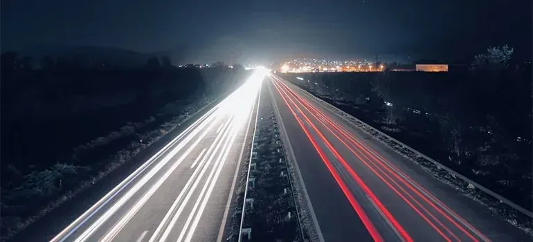 Night highway long-exposure light trails toward city lights