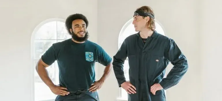 Two smiling movers posing indoors, small Dickies workwear tag visible