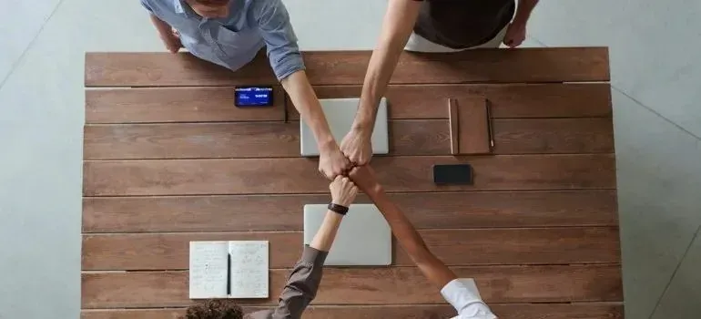 Overhead view of four people fist bumping over table