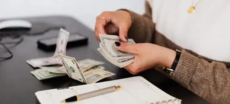 Woman counting dollar bills at desk with planner