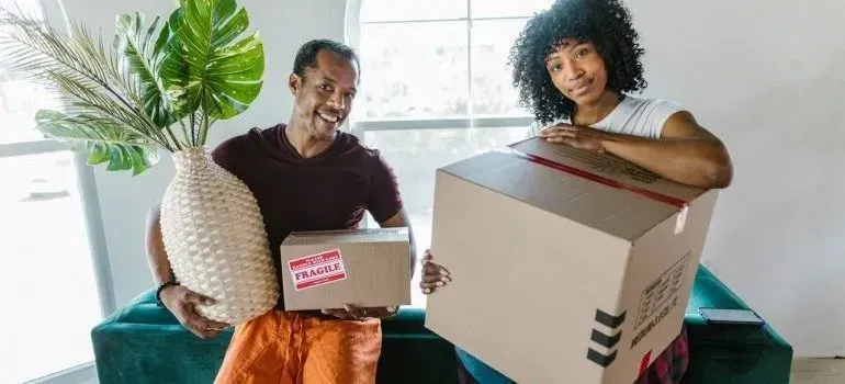Couple holding vase and boxes with fragile stickers