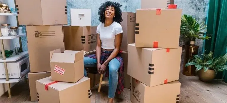 Woman seated among stacked moving boxes with fragile labels