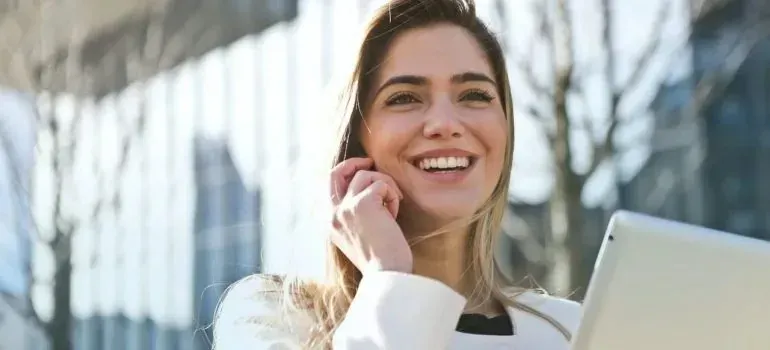 Smiling woman talking on phone outside office buildings