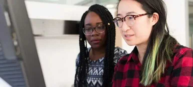 Two women reviewing work on a computer monitor