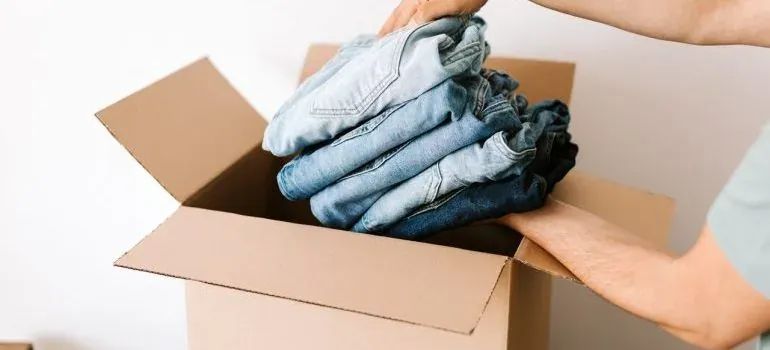 Hands packing folded jeans into box