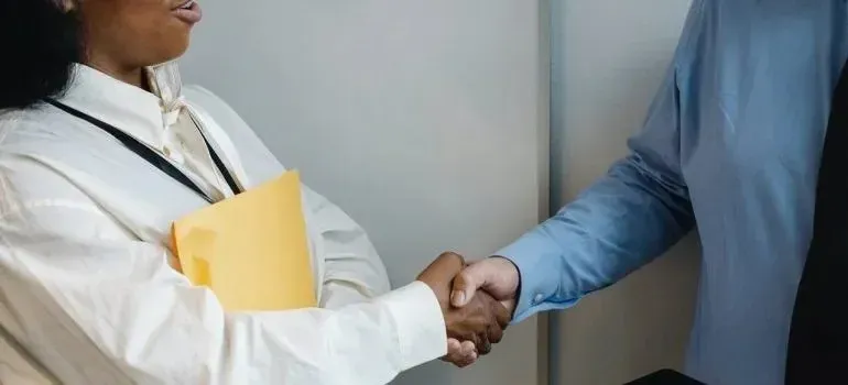 Businesspeople shaking hands, woman holding yellow folder