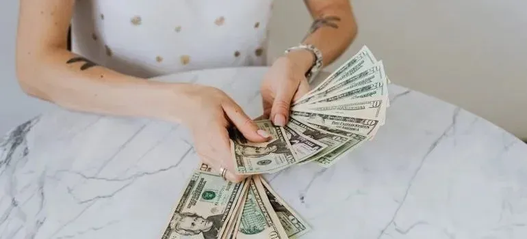 Woman counting fanned dollar bills at marble table