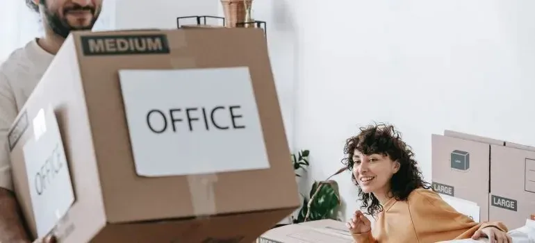 Couple with OFFICE-labeled medium and large moving boxes