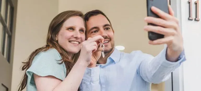 Couple taking selfie with new house keys at door