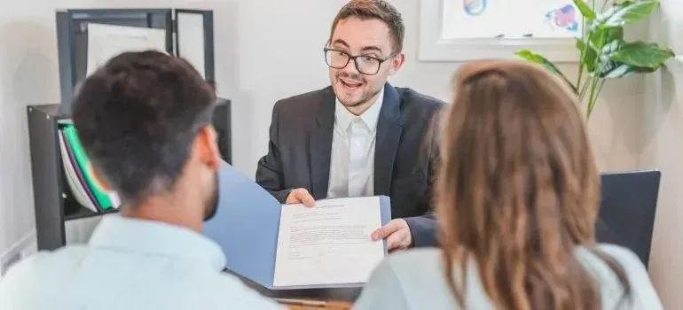 Agent showing contract document to couple in office