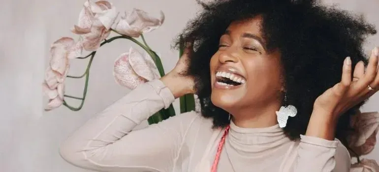 Laughing woman with afro beside orchid flowers