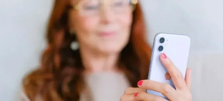 Older woman holding smartphone, face softly blurred