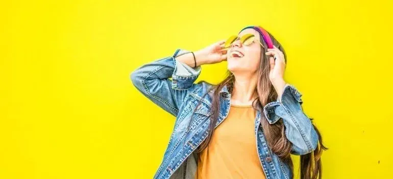 Joyful woman in denim jacket against yellow wall