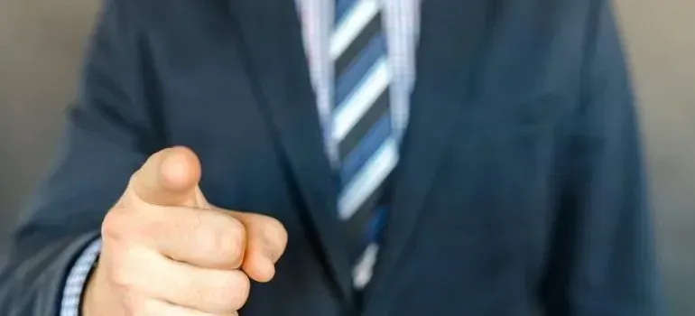 Businessman in suit pointing finger toward camera
