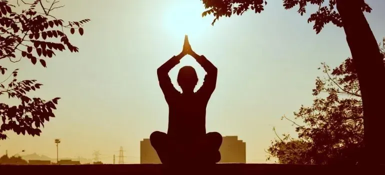 Silhouette of person meditating cross-legged at sunrise