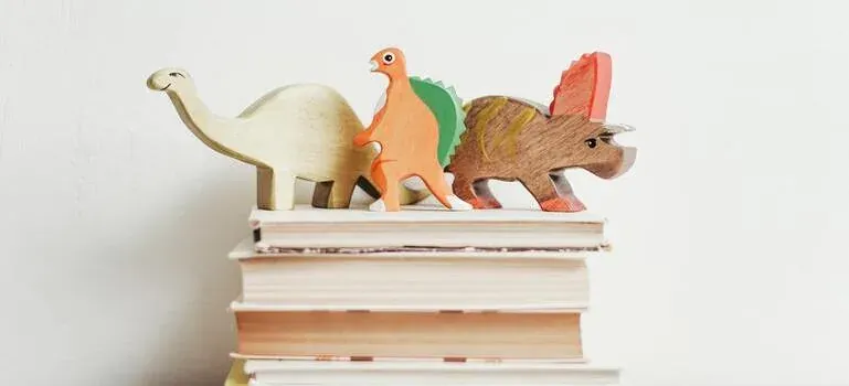 Wooden toy dinosaurs on stacked books