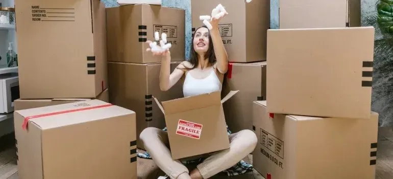 Woman tossing packing peanuts amid labeled moving boxes