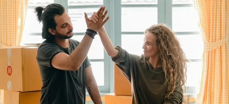 Couple high-fiving among cardboard boxes in new home