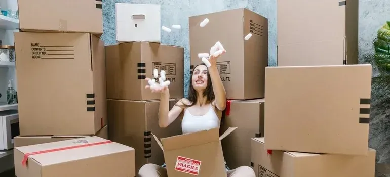 Woman tossing packing peanuts among fragile-labeled boxes