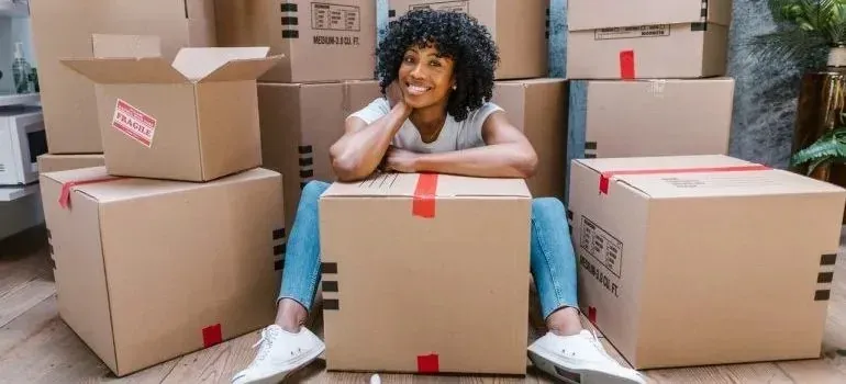 Smiling woman seated among taped boxes with fragile stickers