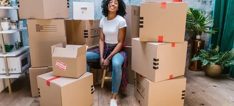 Woman seated among stacked boxes with red fragile labels