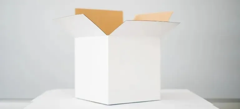 Open white box with kraft paper on white table