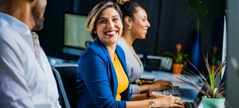 Smiling businesswoman in blue blazer working beside colleagues