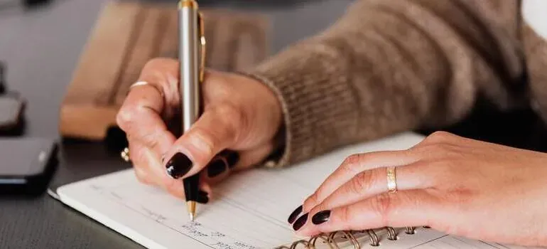 Hands writing in notebook with pen
