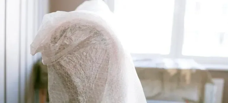 Armchair wrapped in bubble wrap beside bright window