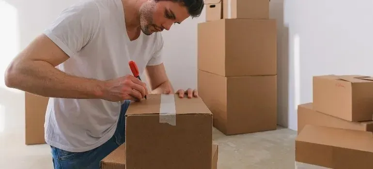 Man labeling sealed moving boxes with red marker