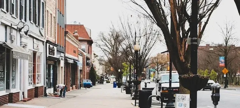 Small-town shopping street with parked vans, bare trees
