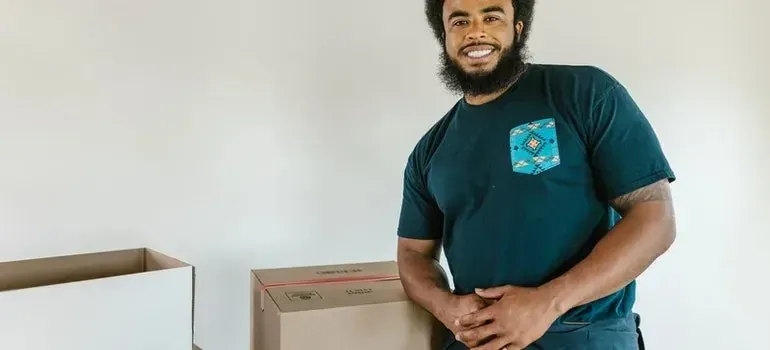 Smiling bearded man leaning on stacked moving boxes
