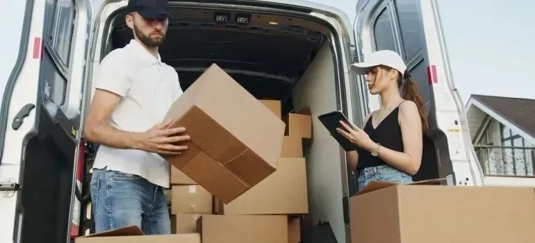 Couple unloading cardboard boxes from unmarked white cargo van