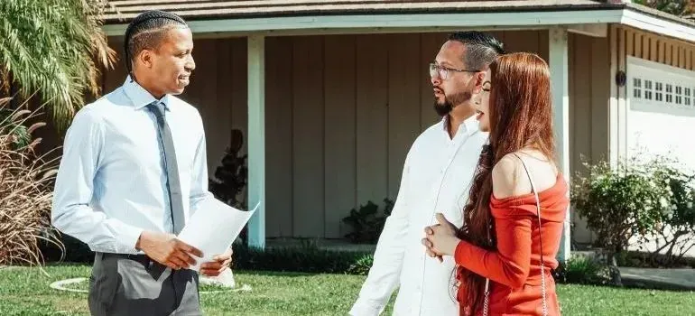 Agent with documents talking to couple outside house