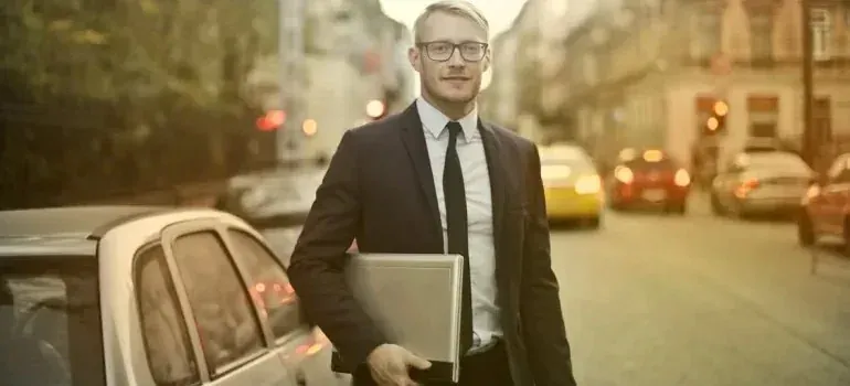Businessman with laptop standing on city street