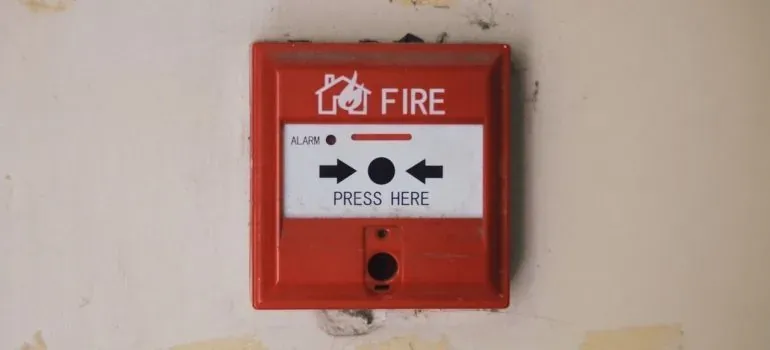 Red fire alarm pull station on weathered wall