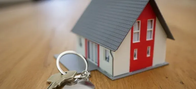 Miniature house model with house keys on wooden table