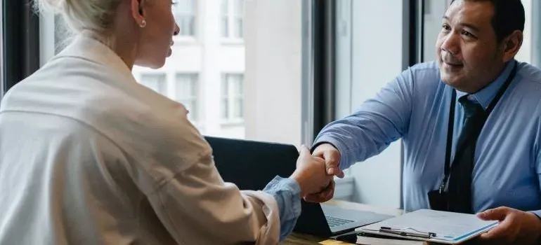 Businessman shaking hands with woman across office desk