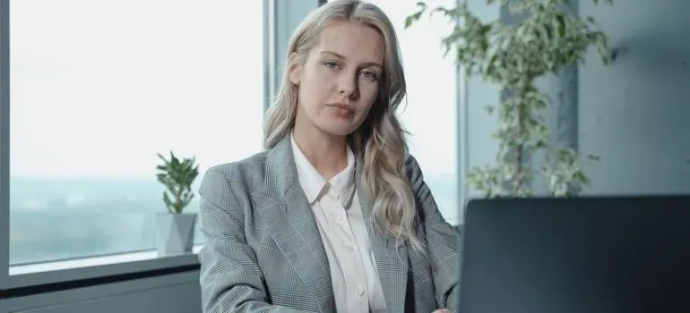 Businesswoman in blazer working at laptop by office window