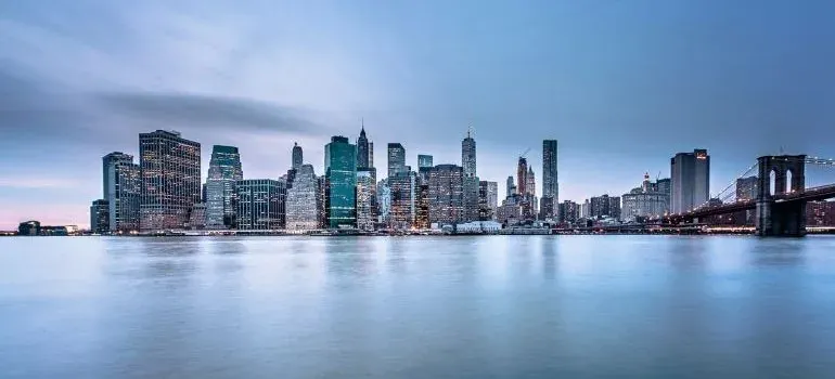 Manhattan skyline across calm water at dusk